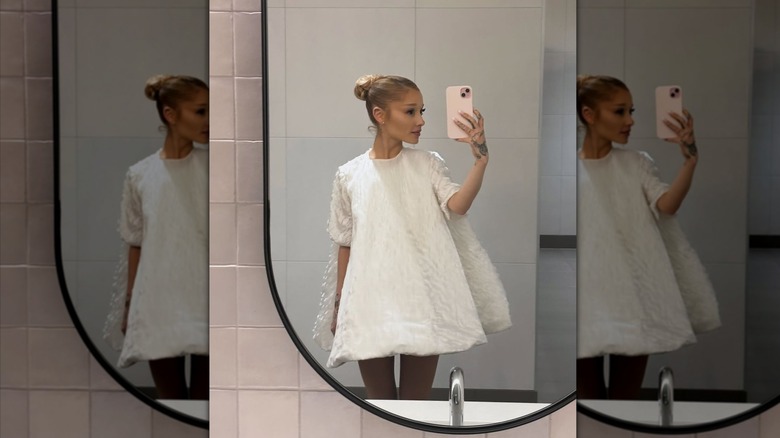 Ariana Grande wears a white puffy dress to take a bathroom selfie.