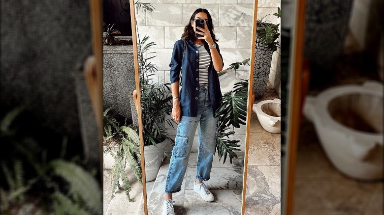 A woman taking a mirror selfie while wearing denim cargo pants