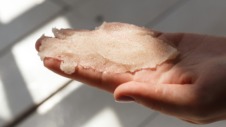 A hand holding a sugar and oil scrub