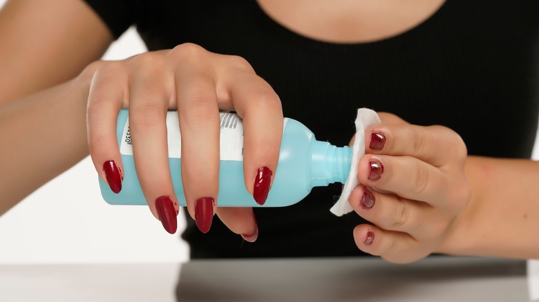 A woman applying acetone nail polish remover to a cotton pad