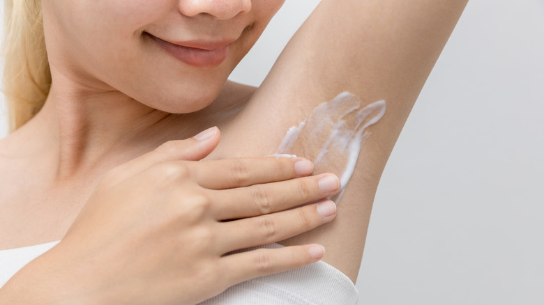 A woman applying hair removal cream to her armpit