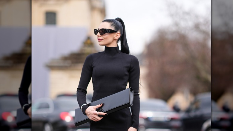 A woman with a high ponytail wearing black sunglasses.