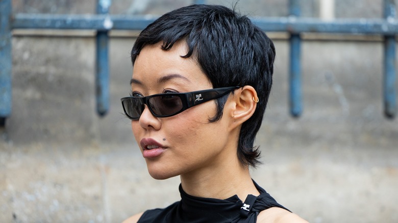 A woman wearing sunglasses with a pixie cut.