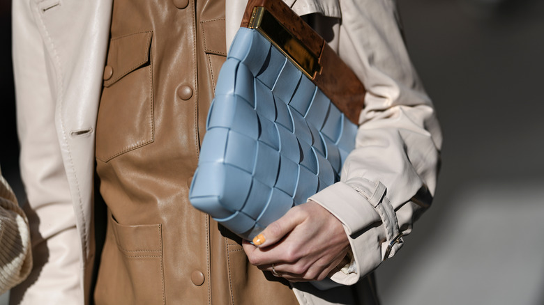 Person holding blue woven clutch