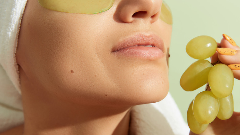 Woman with an eye mask holding grapes