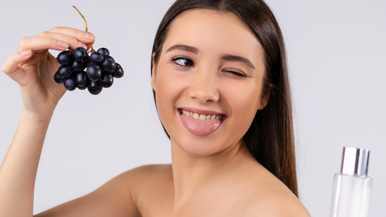 Woman winking and holding grapes 