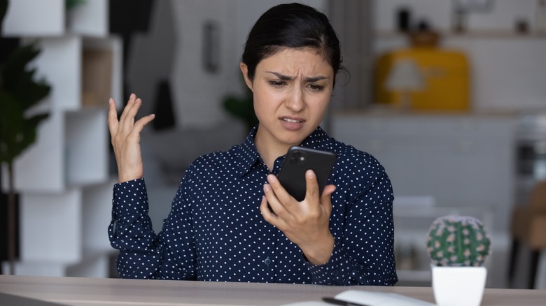 Woman checking her phone and looking confused