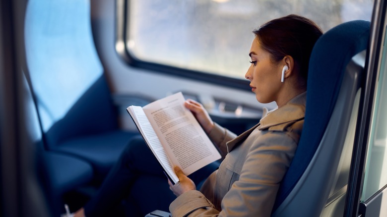woman reading book on train