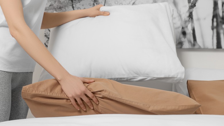 woman changing pillows on bed