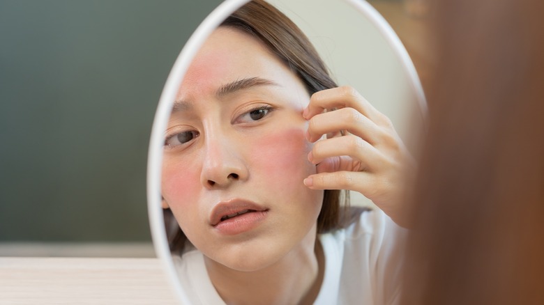 woman looking at skin in the mirror