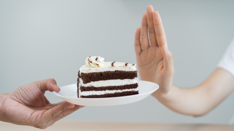 hand rejecting a piece of cake