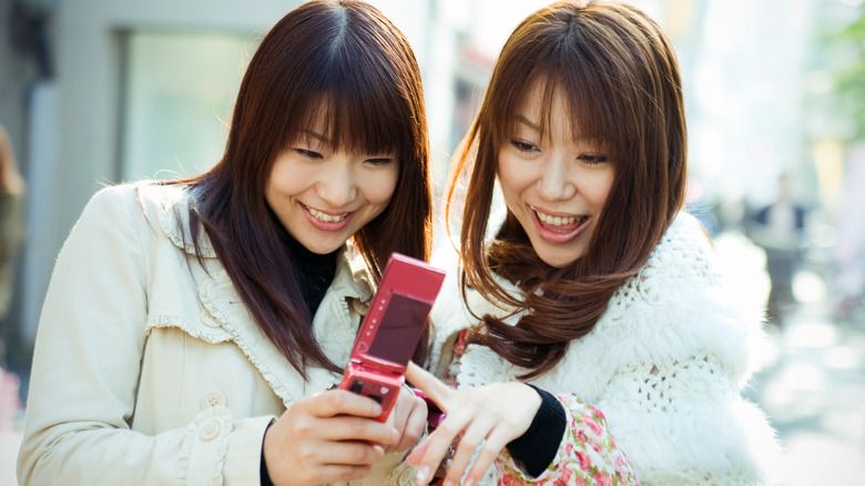 women giggling at flip phone