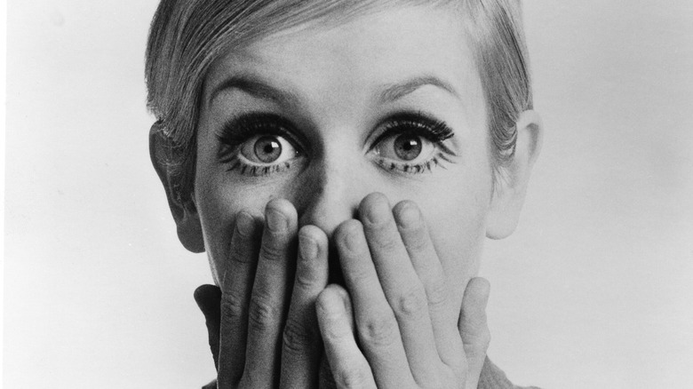 Twiggy hands covering mouth