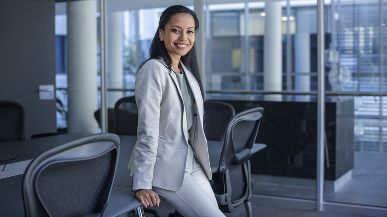 Woman in pantsuit leaning on desk