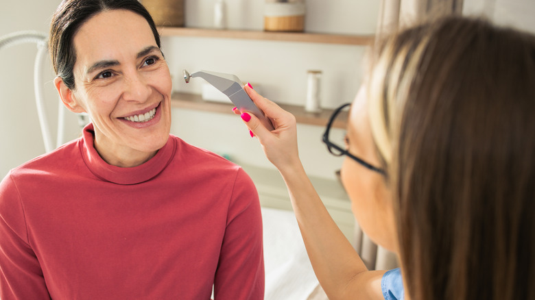 woman smiles as she receives cosmetic service