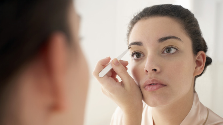 Woman plucking eyebrows