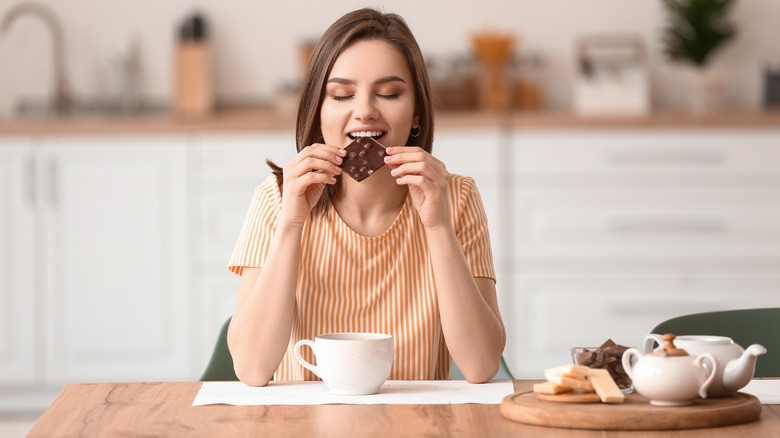 Smiling woman eating chocolate bar