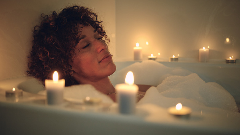 Woman in bath surrounded by candles