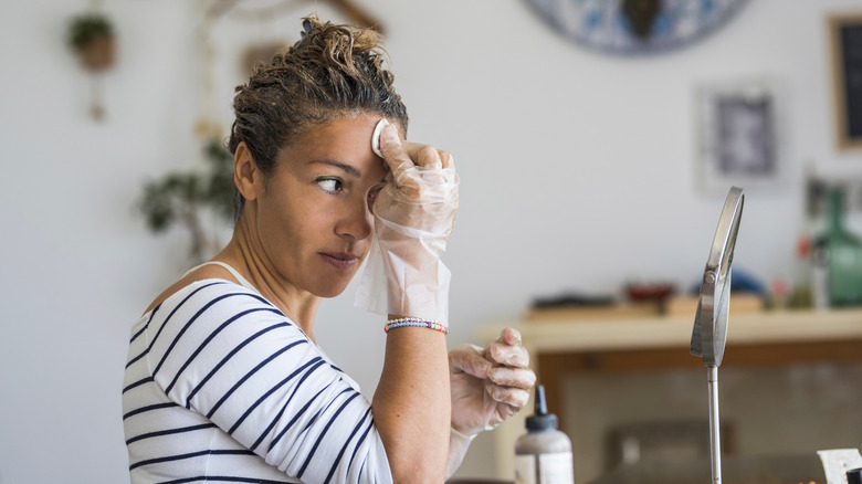 woman washing face with cotton pad