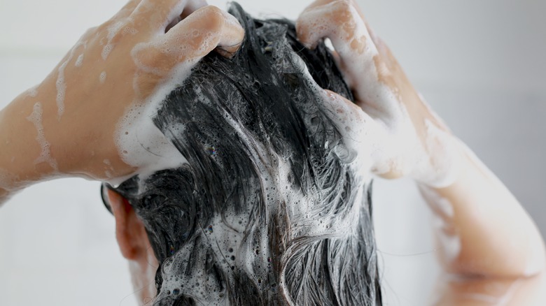 Woman washing hair with shampoo