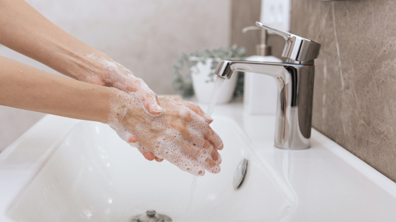 woman washing hands under flowing tap