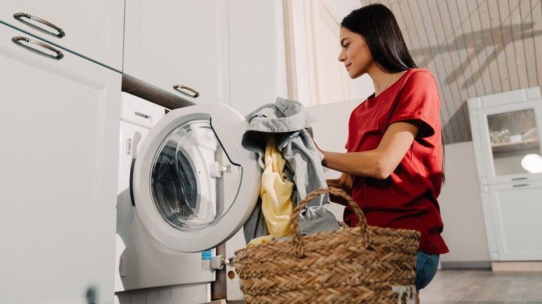 woman putting clothes in washing machine