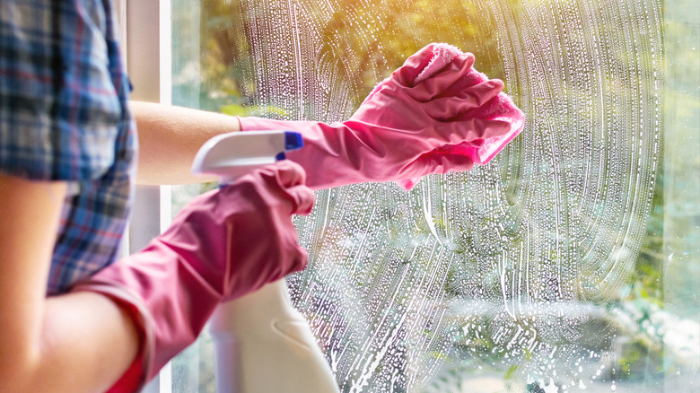 pink gloved hands cleaning window