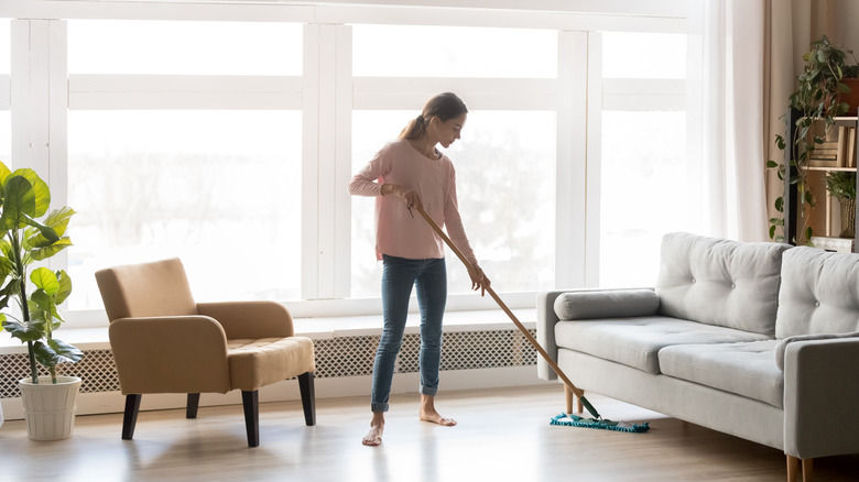 woman mopping wood floor of living room