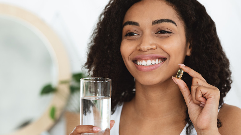 Woman holding a supplement glass of water