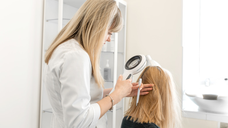 Dermatologist inspecting a woman's scalp