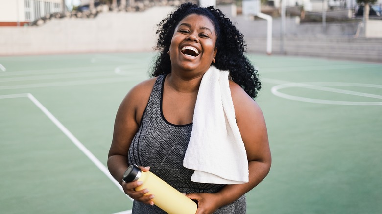 Laughing woman a water bottle and towel