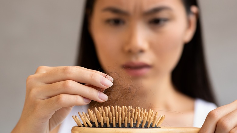 worried woman looking at hair from brush