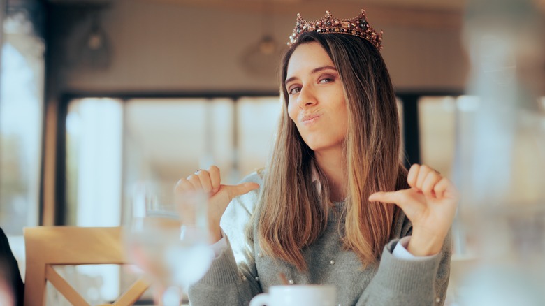 Woman in tiara pointing at herself