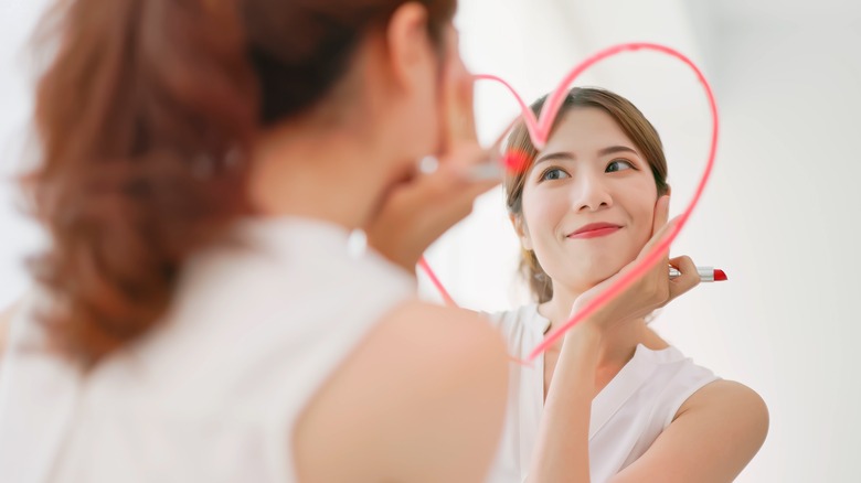 Woman looking in mirror with lipstick heart