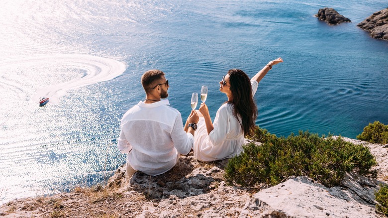 couple drinking beside the ocean 