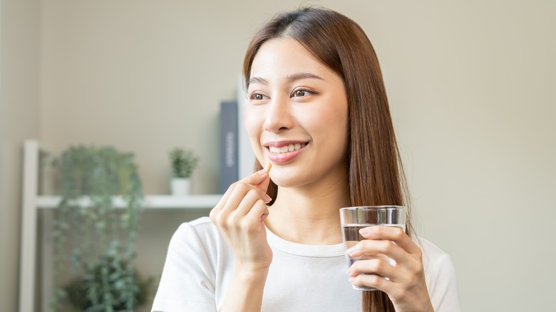 Woman taking supplement with water