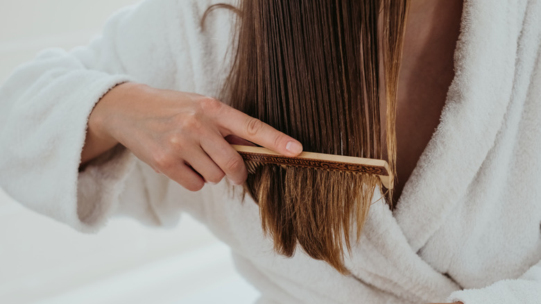 Woman in bathrobe combing hair