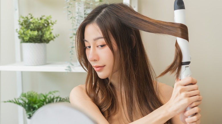 Woman curling hair with iron