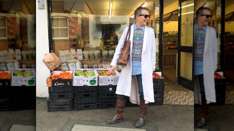 Person wearing white duster over patterned outfit in front of store