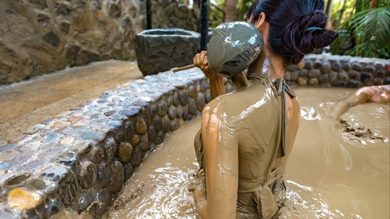 Woman pouring mud in mud bath