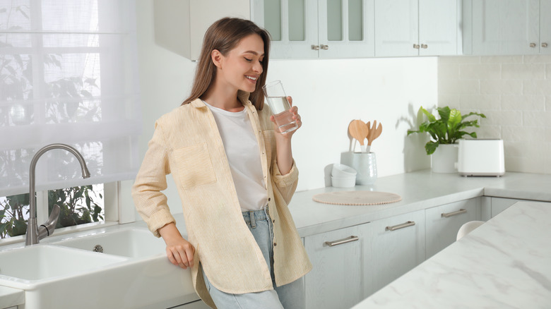 woman drinking water in kitchen