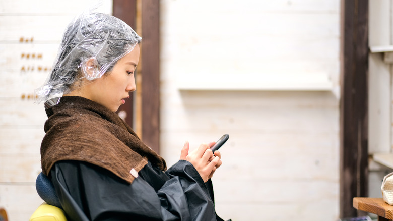 woman using phone at hair salon