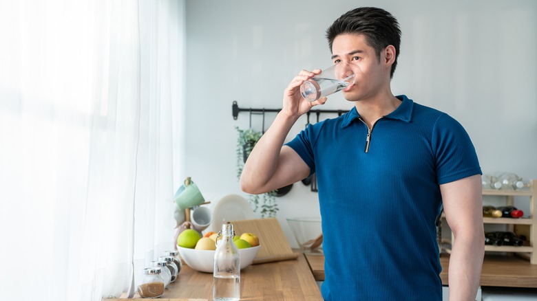 man drinking water in kitchen