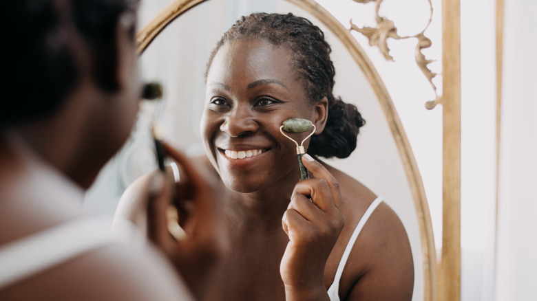 Smiling woman using face roller