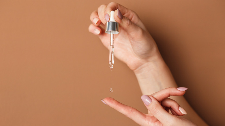 woman holding dropper of serum