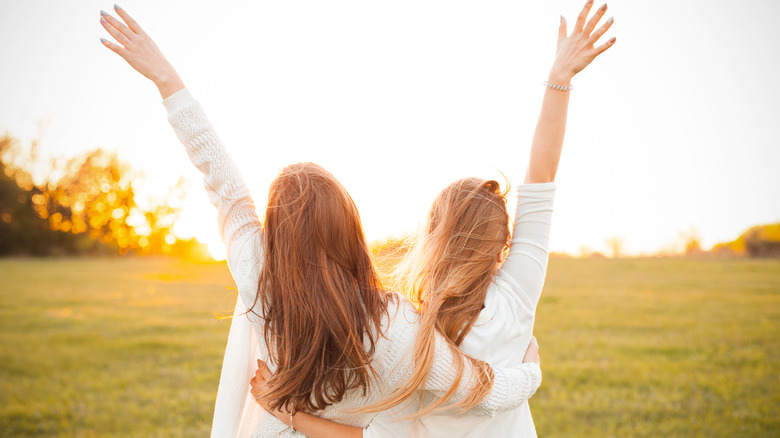 Two friend's backs with arms stretched 