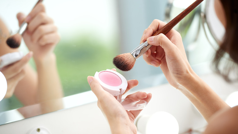 woman dipping into blush makeup