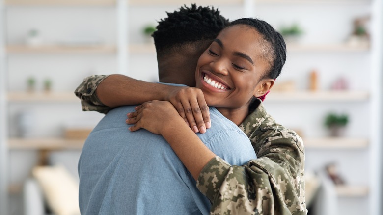 Woman in Army hugging partner 