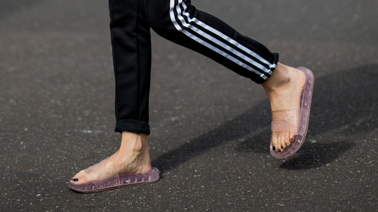 Person wearing black leggings and jelly slides