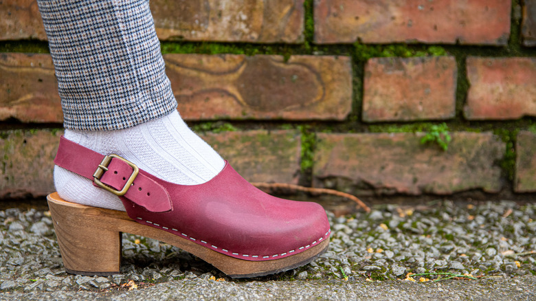 Red clog on a person with plaid leggings